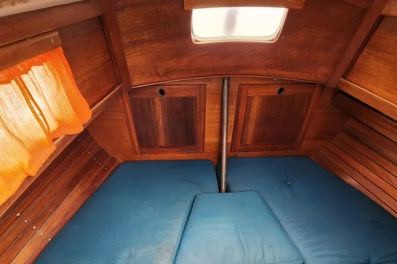 Slide: The Image of 1974 Hallberg-Rassy Rasmus 35 cabin interior with blue cushions and wooden paneling. - 27