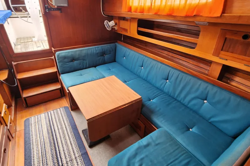 Slide: The Image of 1974 Hallberg-Rassy Rasmus 35 interior with blue seating and wooden table. - 35