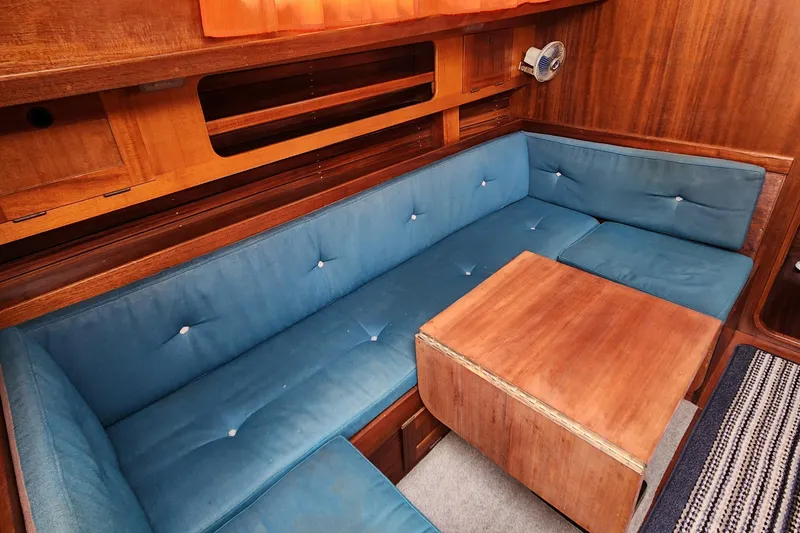 Slide: The Image of Interior of 1974 Hallberg-Rassy Rasmus 35 with blue cushioned seating and wooden table. - 36