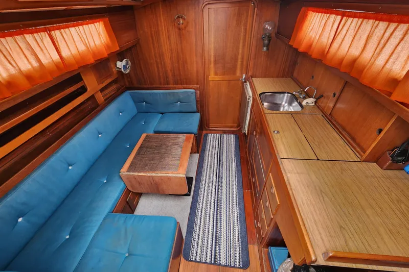 Slide: The Image of Interior of 1974 Hallberg-Rassy Rasmus 35 yacht with blue seating and wooden finishes. - 37