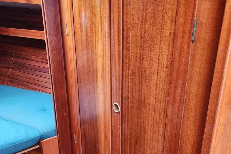 Slide: The Image of Wooden interior of a 1974 Hallberg-Rassy Rasmus 35 sailboat with blue cushioned seating. - 48