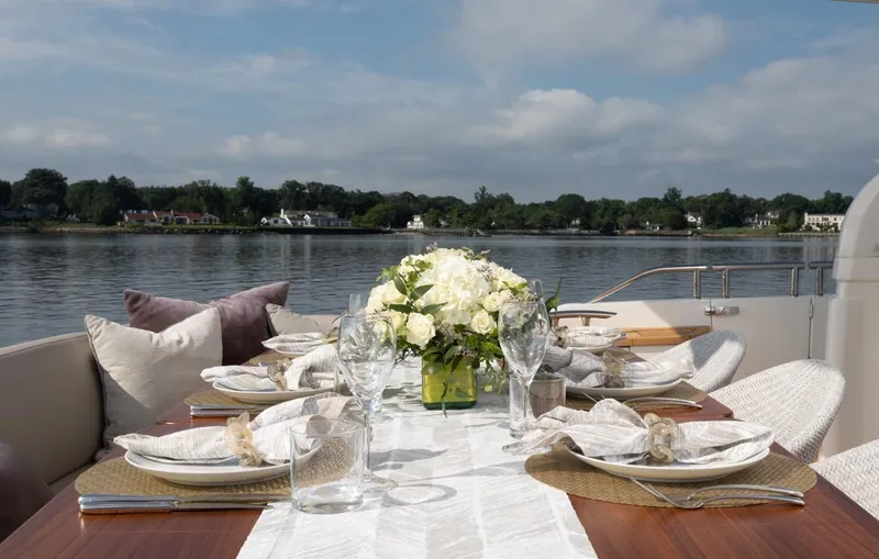 Slide: The Image of Elegant dining setup on 2019 Princess Y88 Motor Yacht, featuring floral centerpiece and scenic water view. - 29
