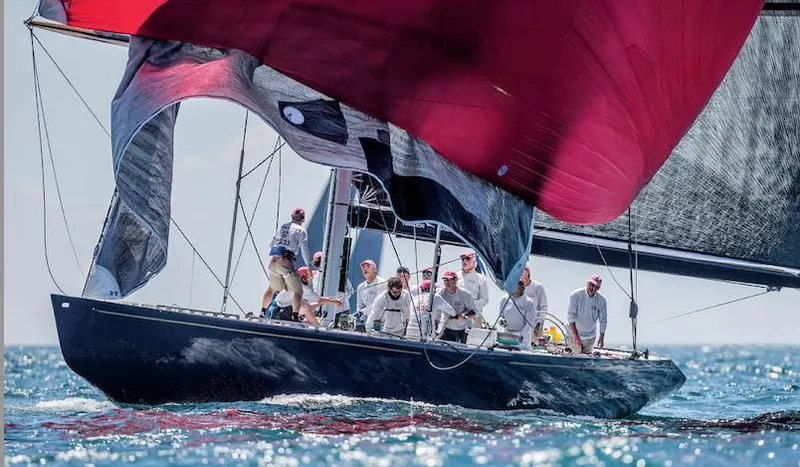 Slide: The Image of 1982 Sailboat 12 Meter racing with crew, vibrant red sails, on open sea. - 3