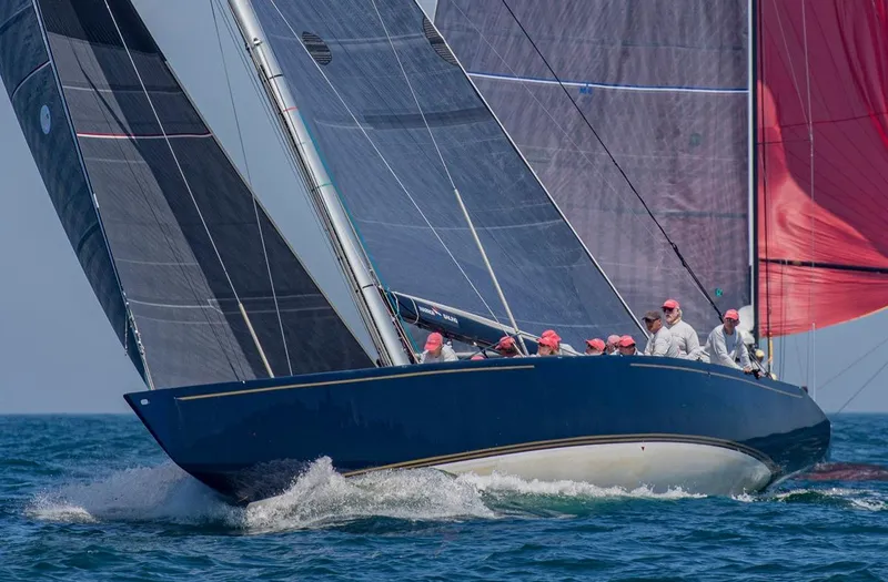 Slide: The Image of 1982 Sailboat 12 Meter racing on open water with crew in red caps. - 5