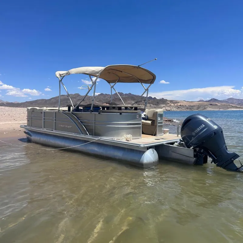 The Image of 2018 Starcraft 24 CXE Tritoon boat on sandy shore under clear blue sky. - 0