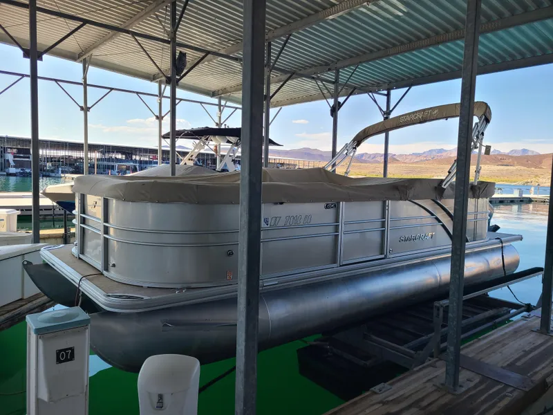 Slide: The Image of 2018 Starcraft 24 CXE Tritoon docked under a covered marina. - 13