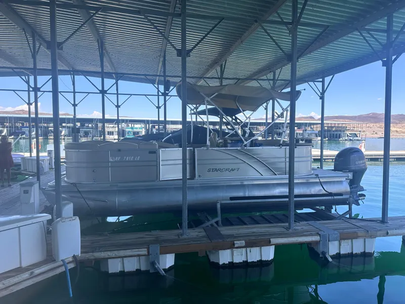Slide: The Image of 2018 Starcraft 24 CXE Tritoon docked under a covered marina. - 2