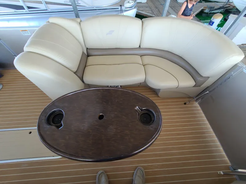 Slide: The Image of 2018 Starcraft 24 CXE Tritoon interior with beige seating and oval table. - 4
