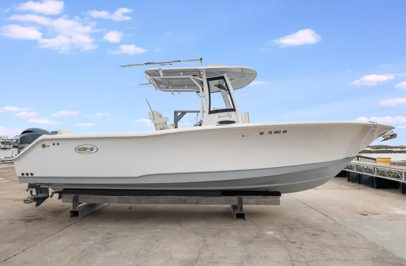Slide: The Image of 2022 Sea Hunt Gamefish 27CE boat on a dock under a clear blue sky. - 0