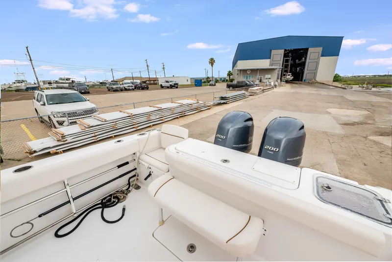 Slide: The Image of 2022 Sea Hunt Gamefish 27CE boat with dual engines, docked near a warehouse. - 10