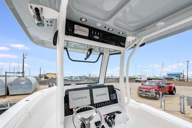 Slide: The Image of 2022 Sea Hunt Gamefish 27CE boat dashboard with Garmin displays at a marina. - 16