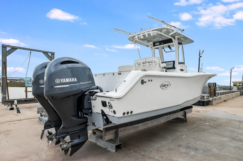 Slide: The Image of 2022 Sea Hunt Gamefish 27CE boat with dual Yamaha engines on a dock. - 7