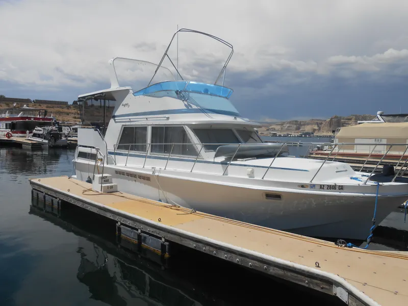 The Image of 1981 Uniflite Cabin Cruiser docked at marina under cloudy sky. - 1