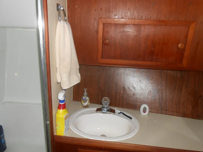 Slide: The Image of 1981 Uniflite Cabin Cruiser bathroom with sink, wooden cabinets, and cleaning supplies. - 13
