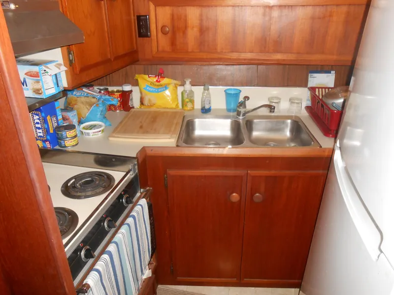 Slide: The Image of 1981 Uniflite Cabin Cruiser kitchen with stove, sink, and wooden cabinetry. - 17