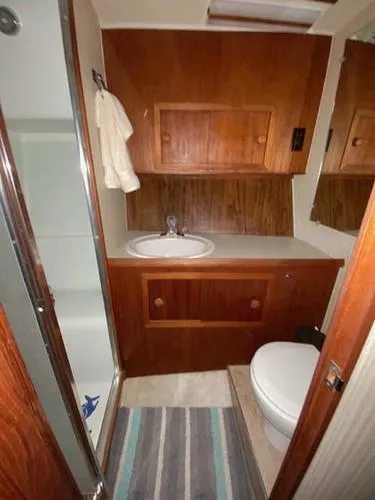 Slide: The Image of 1981 Uniflite Cabin Cruiser bathroom with wood cabinetry, sink, and shower. - 23