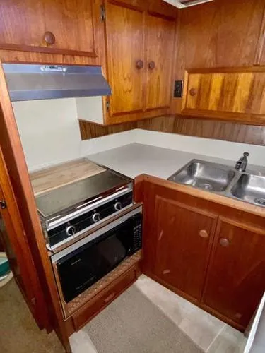 Slide: The Image of 1981 Uniflite Cabin Cruiser kitchen with wood cabinets, stove, and double sink. - 31