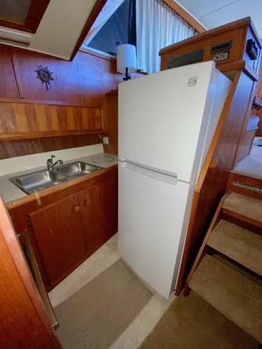 Slide: The Image of 1981 Uniflite Cabin Cruiser kitchen with sink, white refrigerator, and wooden cabinetry. - 32
