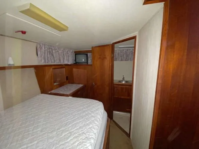 Slide: The Image of 1981 Uniflite Cabin Cruiser interior with bed, wood paneling, and small TV. - 38