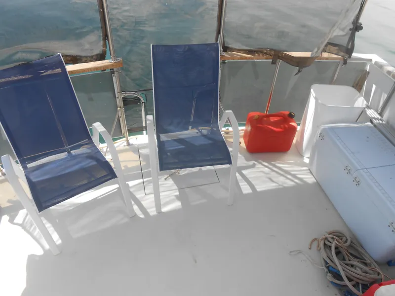 Slide: The Image of 1981 Uniflite Cabin Cruiser deck with blue chairs, red fuel can, and coiled rope. - 4