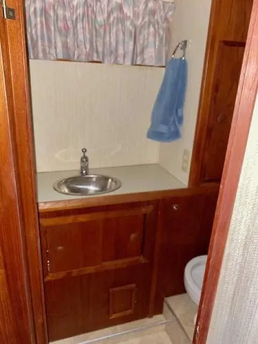 Slide: The Image of 1981 Uniflite Cabin Cruiser bathroom with sink, wooden cabinets, and blue towel. - 40