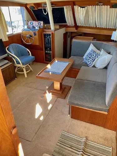 Slide: The Image of 1981 Uniflite Cabin Cruiser interior with seating, table, and helm, featuring nautical decor. - 41