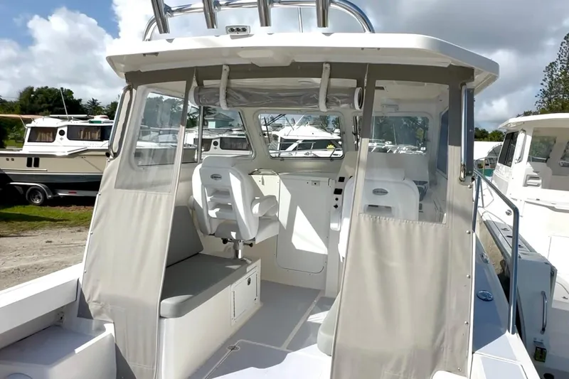 Slide: The Image of 2024 NorthCoast 255HT boat interior with seating and helm, docked under cloudy sky. - 11