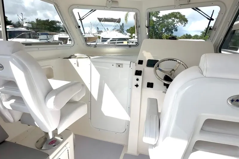 Slide: The Image of 2024 NorthCoast 255HT boat interior with steering wheel and white seating. - 14