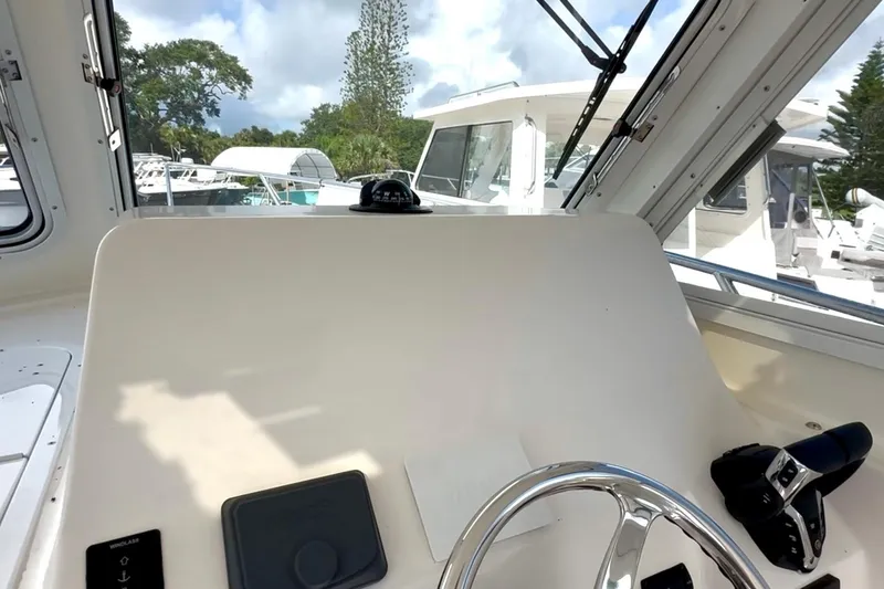 Slide: The Image of 2024 NorthCoast 255HT boat helm with steering wheel and controls, docked with other boats. - 20