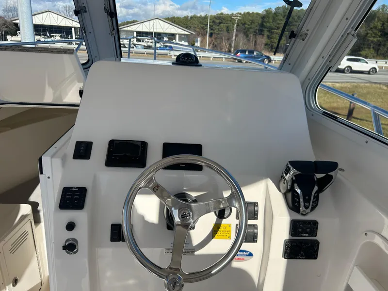 Slide: The Image of 2024 NorthCoast 255HT boat helm with steering wheel and controls. - 24