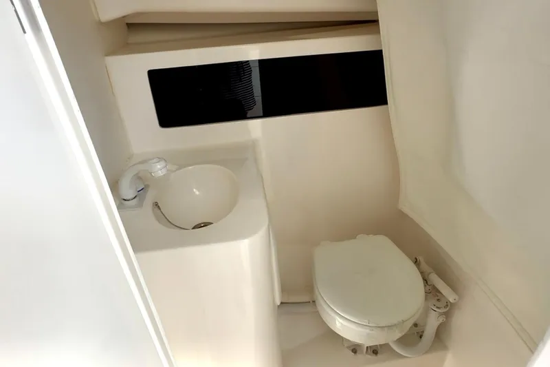 Slide: The Image of 2024 NorthCoast 255HT boat interior with compact bathroom, featuring sink and toilet. - 33