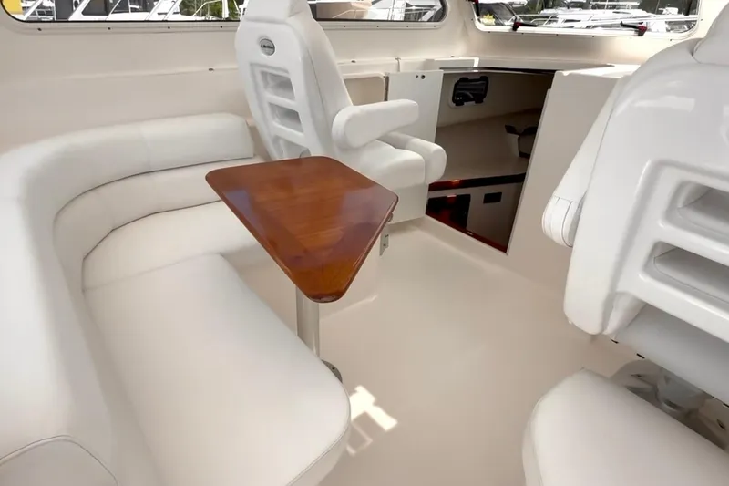 Slide: The Image of 2024 NorthCoast 285HT boat interior with white seating and wooden table. - 17