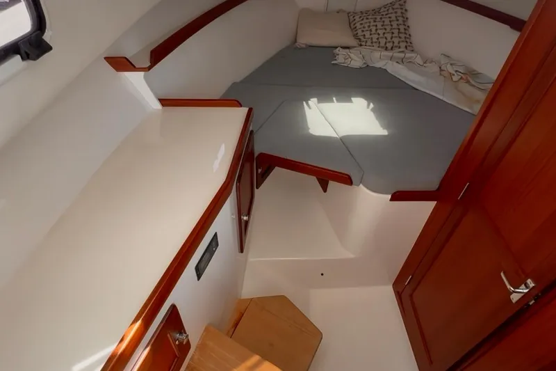 Slide: The Image of 2024 NorthCoast 285HT cabin interior with cozy bed and wooden cabinetry. - 22