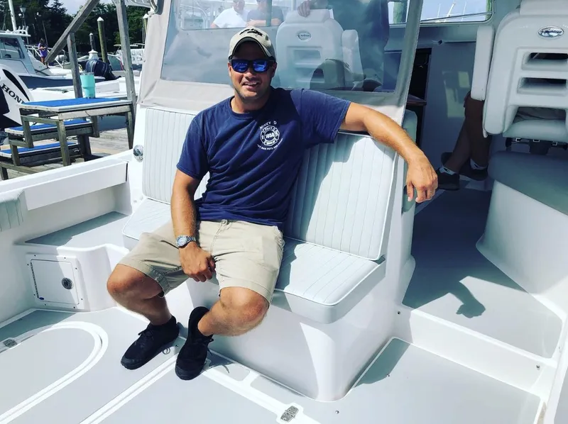 Slide: The Image of Man relaxing on a 2024 NorthCoast 285HT boat, docked at a marina. - 33