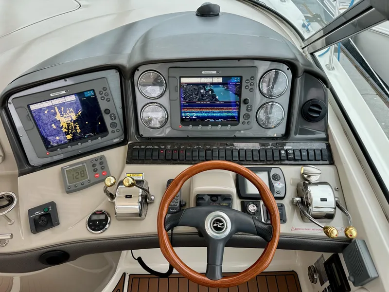 Slide: The Image of 2006 Sea Ray 44 Sundancer helm with dual navigation screens and wooden steering wheel. - 22