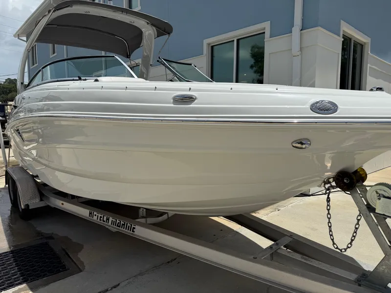 The Image of 2023 Crownline 250 XSS boat on trailer, parked outside a building. - 1