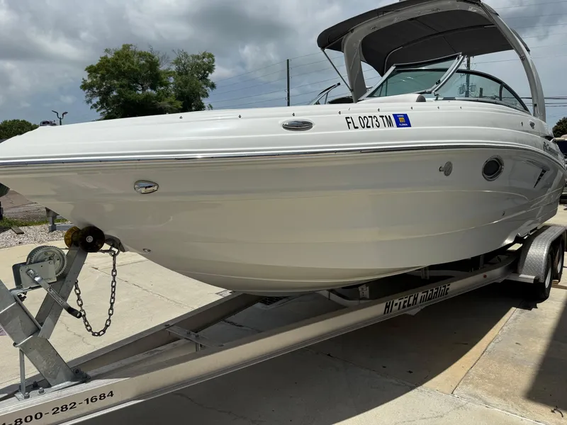 Slide: The Image of 2023 Crownline 250 XSS boat on trailer, white exterior, parked outdoors. - 2