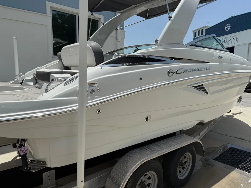 Slide: The Image of 2023 Crownline 250 XSS boat on trailer, sleek design, white exterior, parked outdoors. - 4