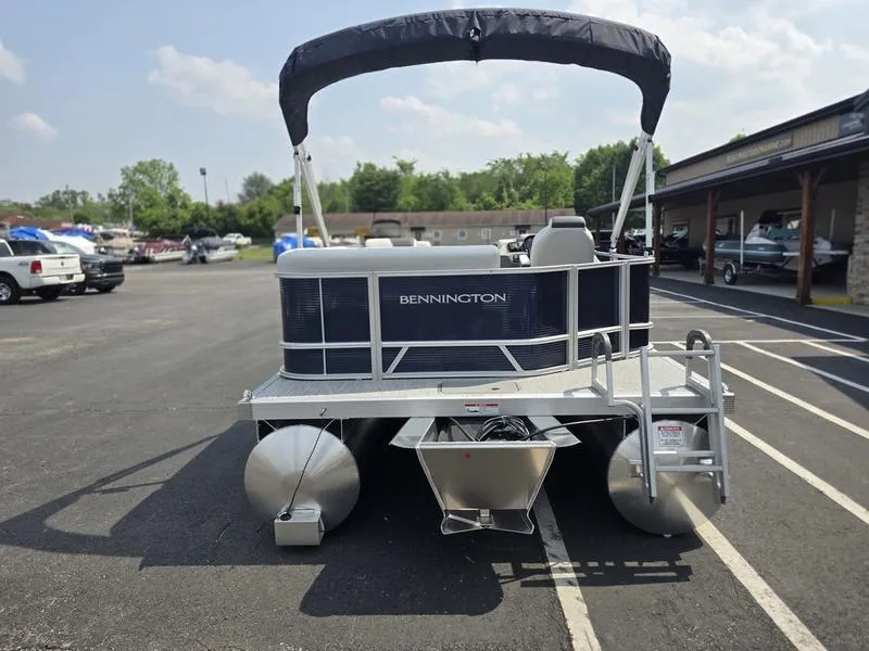 Slide: The Image of 2025 Bennington 20 SL pontoon boat with canopy, parked in a lot on a sunny day. - 5