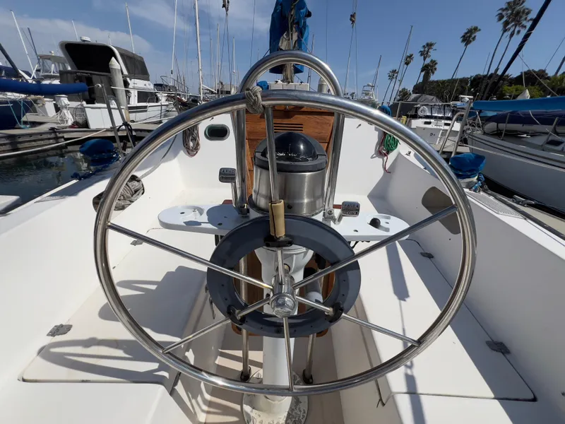 Slide: The Image of 1986 Catalina 30 sailboat helm with stainless steel wheel, docked in a marina. - 13