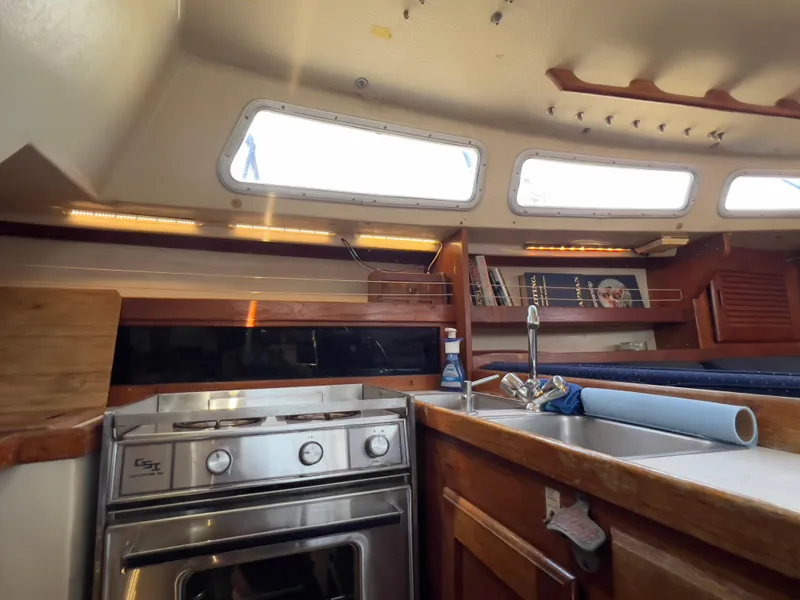 Slide: The Image of Interior of 1986 Catalina 30 sailboat kitchen with stove, sink, and wooden cabinetry. - 18