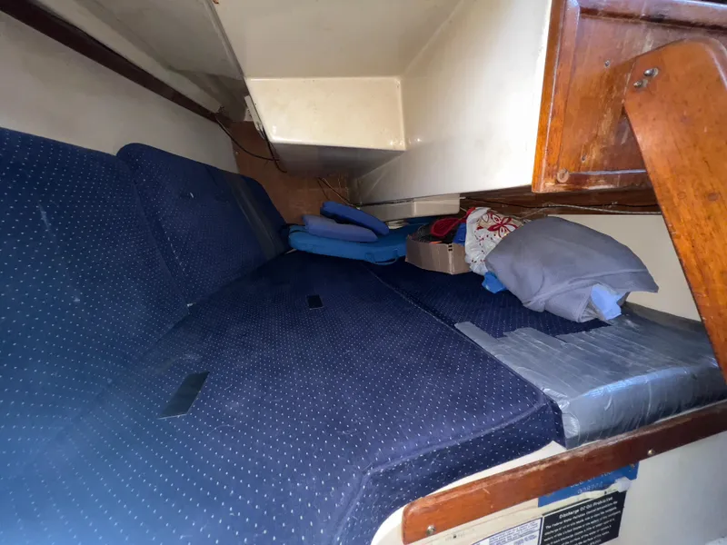 Slide: The Image of Interior cabin of a 1986 Catalina 30 sailboat with blue cushions and wooden accents. - 21