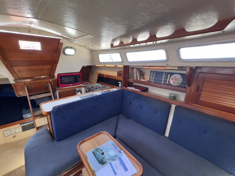 Slide: The Image of Interior of a 1986 Catalina 30 sailboat with blue seating and wooden accents. - 23