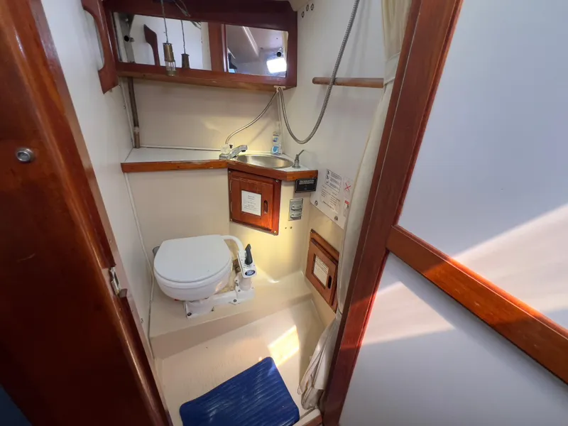 Slide: The Image of 1986 Catalina 30 sailboat bathroom with toilet, sink, and wooden accents. - 26
