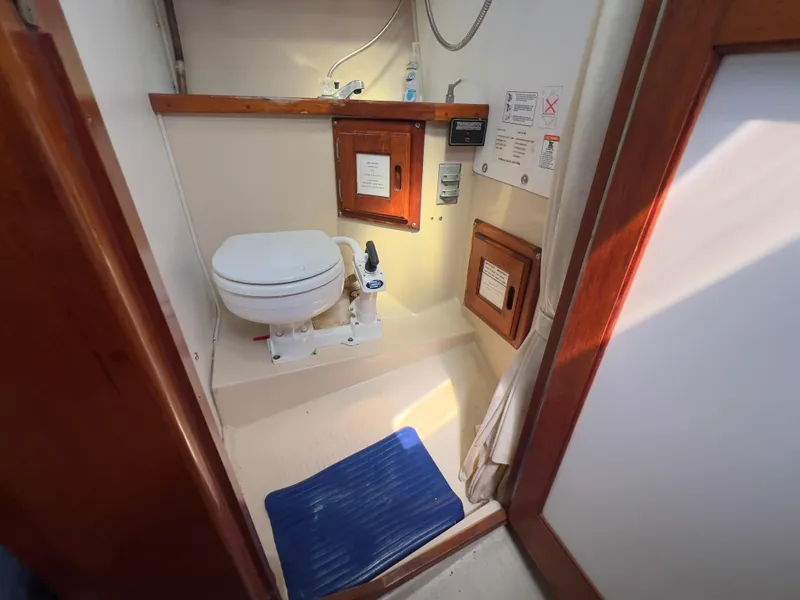 Slide: The Image of 1986 Catalina 30 boat bathroom with toilet, wooden accents, and blue mat. - 28