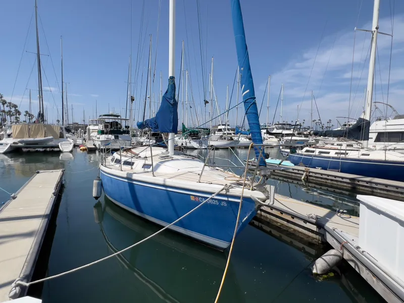 Slide: The Image of 1986 Catalina 30 sailboat docked in a marina, surrounded by other boats. - 3