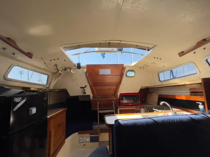 Slide: The Image of Interior of a 1986 Catalina 30 sailboat, featuring a cozy cabin with kitchen amenities. - 33