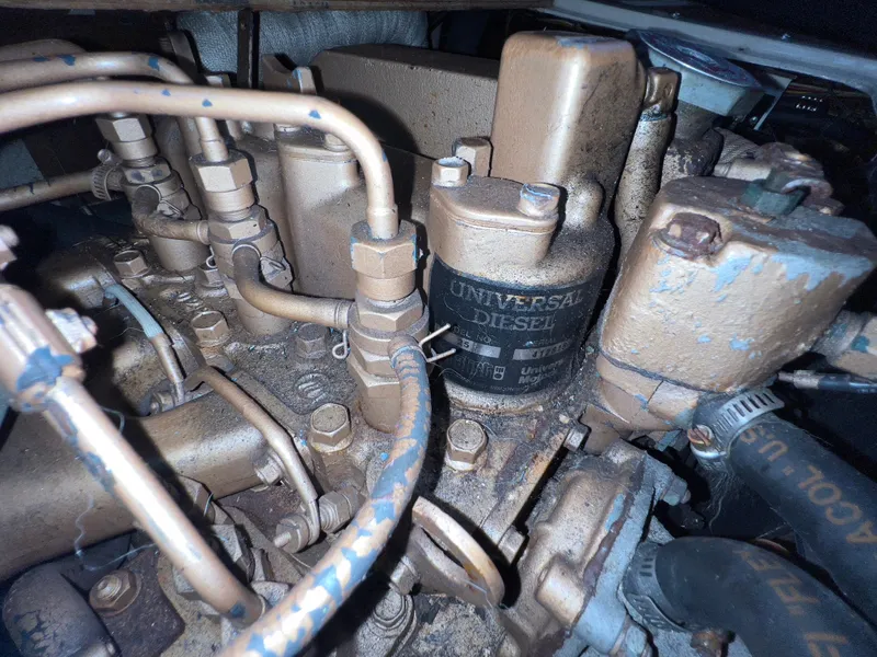 Slide: The Image of 1986 Catalina 30 engine compartment with Universal diesel engine components and pipes. - 35