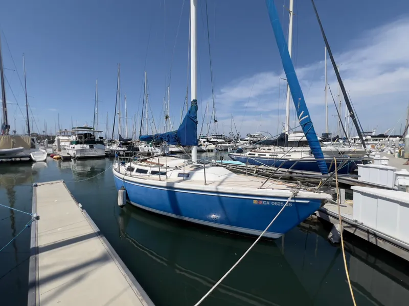 Slide: The Image of 1986 Catalina 30 sailboat docked in marina, blue hull, clear sky background. - 4