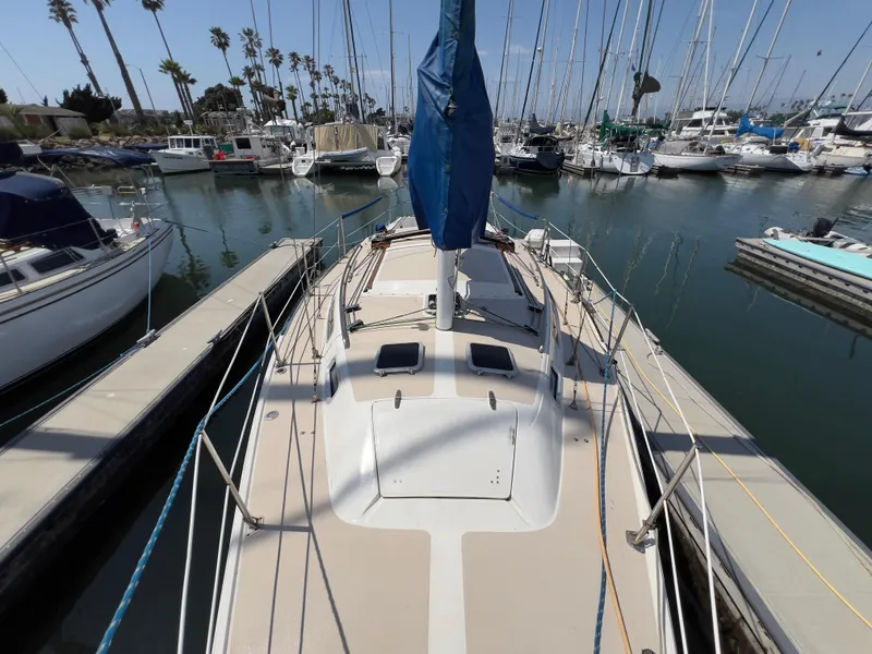 Slide: The Image of 1986 Catalina 30 sailboat docked in marina, surrounded by other boats and palm trees. - 6